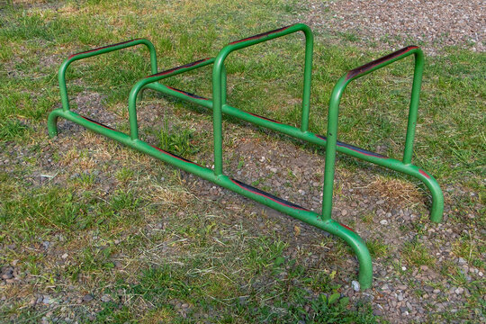 Green outdoor parallel bars in a public park, designed for calisthenics, dips, bodyweight training, and fitness exercise in an open-air setting.