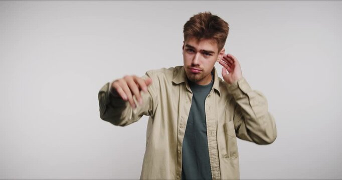 Young man adjusts his hair in different positions in a simple studio setting during daytime