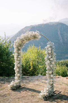 Intimate outdoor elopement featuring floral arch and mountain scenery in golden sunlight