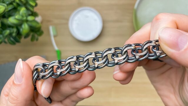 A close-up of a woman's hands holding a massive, tarnished silver bracelet next to household cleaning products.