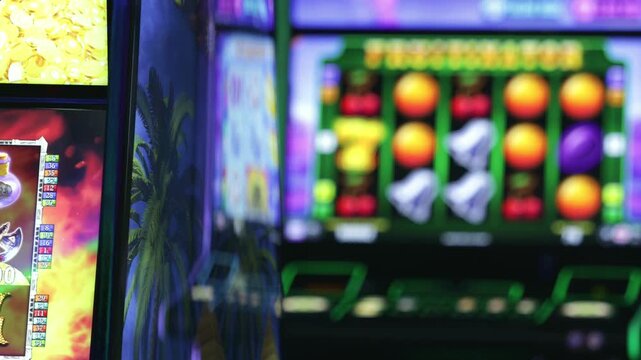 Blurred casino slot machines with colorful illuminated screens. Gambling, betting, gaming industry, luck, risk, entertainment, addiction and nightlife concept.