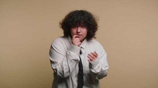 Young person shows nervousness and hesitation in a simple indoor setting with light brown background