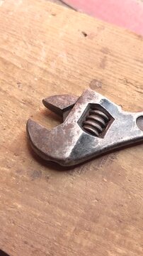 Old adjustable wrench lying on wooden workbench surface