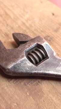 Old adjustable wrench lying on wooden workbench surface
