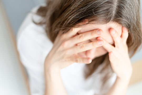 Close up of woman showing severe anxiety and worry about her graying hair. mature adult displays deep emotional pain over silver strands appearing. Mother cannot accept visible sign of getting older.