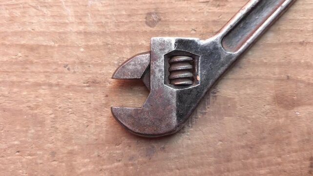 Old adjustable wrench lying on wooden workbench surface
