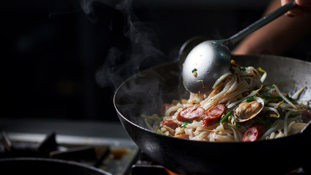 Koch bereitet gebratene Mee Goreng Nudeln im Wok zu