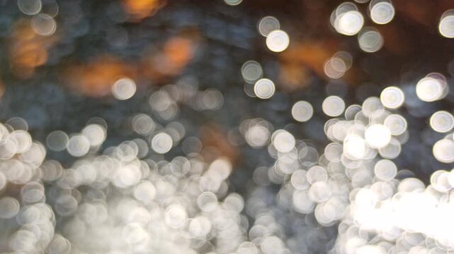 Artistic blur and defocused view of shimmering water ripples under daylight, highlighting sparkling reflections and abstract optical effects on the water surface.