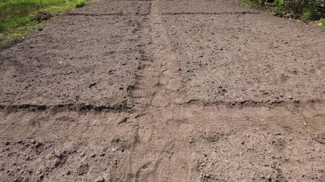 Walking on footpath between garden beds with footprints in loose soil.