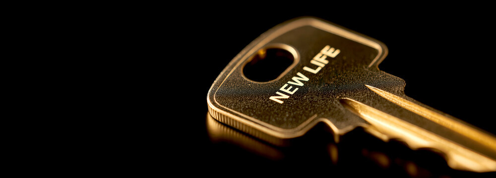 Close up of golden key with text New Life on black reflective background, concept of future, hope and business solution