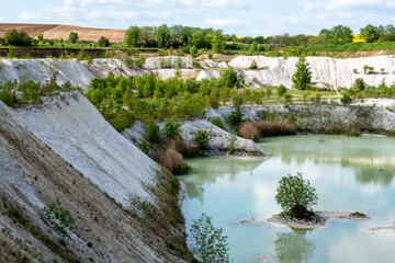 Fototapeta premium Blue quarry lake surrounded by sandy cliffs and mining landscape