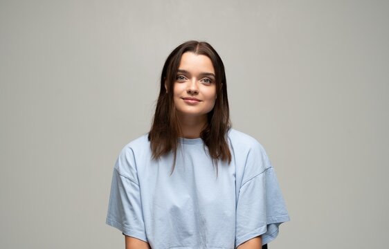 Young woman with a calm expression posing for a portrait in a studio against a neutral background