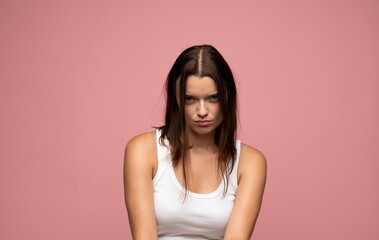 Obraz premium Young brunette woman feeling frustrated and annoyed, expressing anger with a serious facial expression on a pink background