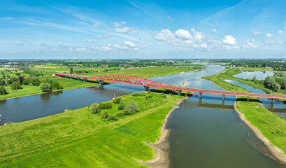 Obraz premium Aerial view of the Hanzeboog (Hanseatic Arch), a combined railway and cycle bridge spanning the IJssel river. The bridge was opened in June 2011