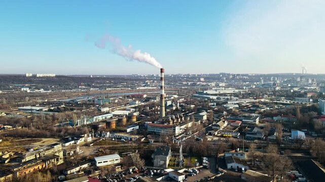 Aerial view of industrial zone with smoking chimney in urban city landscape.