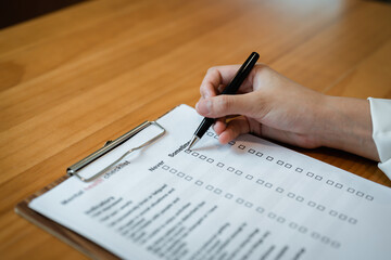 Person filling mental health checklist on clipboard with pen, psychological assessment, self...
