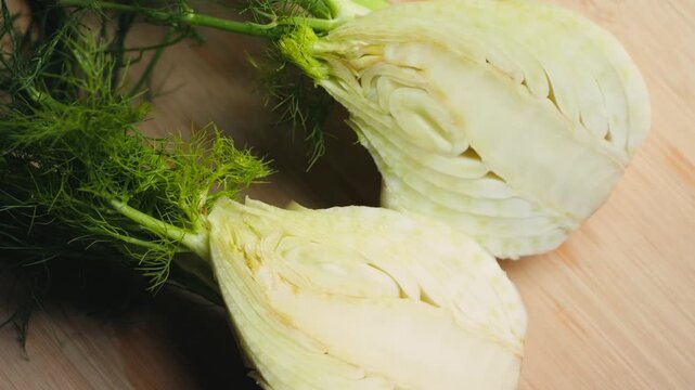 Close-up of fresh fennel cut in half on a wooden cutting board. Healthy vegetable ingredient, cooking preparation and organic food concept. High quality 4k footage