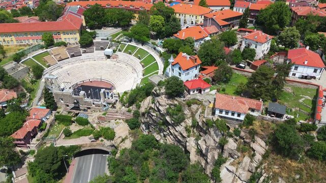 aerial drone panorama over the ancient Roman Theatre of Philippopolis and traditional houses with red roofs in the old town hill district of Plovdiv, Bulgaria