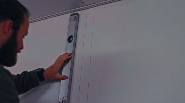 A Worker Carefully Measures and Aligns a Wall Panel Using a Level, Showing a Precise Step in
Interior Installation - Close Up