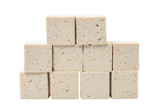 Stack of ten raw firm tofu cubes arranged in a pyramid shape against a solid black background, showing porous texture and off-white color