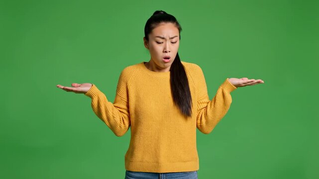 Confused young woman shrugging shoulders with uncertain expression on green screen