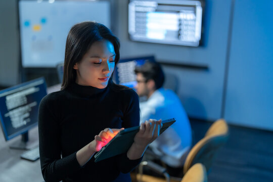 Female Developer Using Tablet In Dark Technology Office