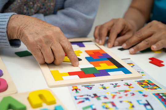 Asian elderly woman playing game with caregiver for train memory.