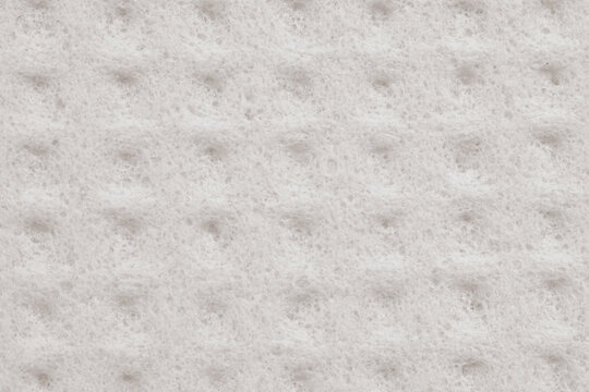 Macro photography of a light grey cellulose sponge with a rhythmic geometric pattern. The soft woven structure of polymer fibers creates a clean 3D network