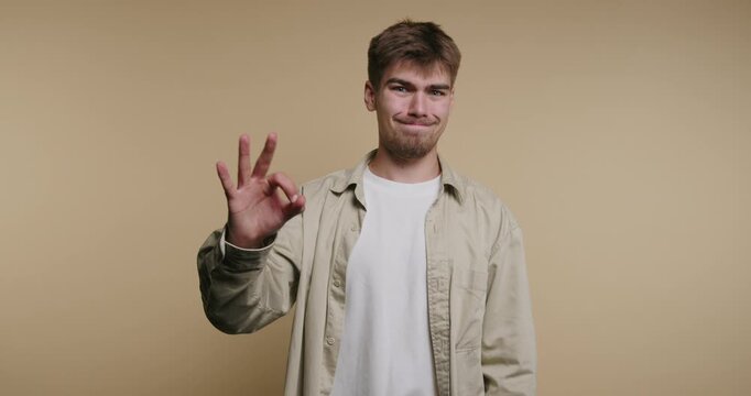 Man shows various hand gestures inside a room with plain wall while expressing different emotions and reactions
