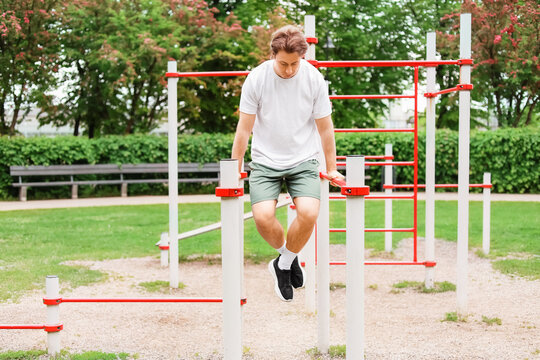 Fit man doing dips at a public outdoor gym. Enjoying an active lifestyle, bodyweight training, strength exercise, and healthy habits