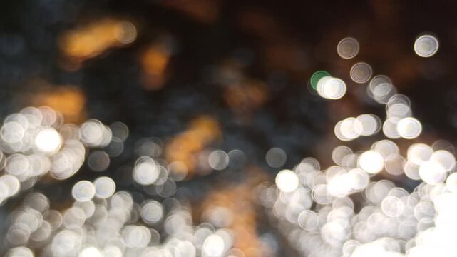 Artistic blur and defocused view of shimmering water ripples under daylight, highlighting sparkling reflections and abstract optical effects on the water surface.