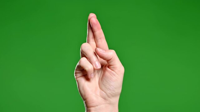 Hand gesture with fingers crossed for good luck isolated on green screen background