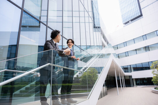 A business scene featuring a young employee and their supervisor building a trusting relationship through conversation while taking a break in front of a building