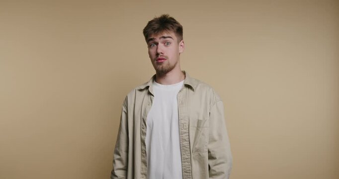 Young man stands against a plain wall and expresses various emotions in a short period of time