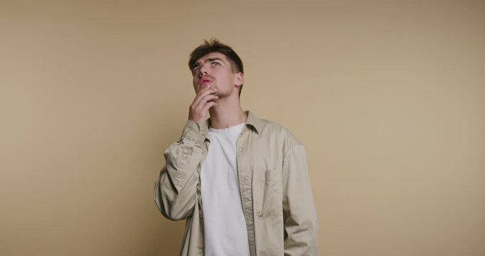 Man thinks and gestures in front of a plain wall while showing different expressions and thoughts during a short moment