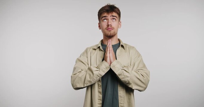 Man shows gratitude and appreciation through hand gestures in a simple studio setting