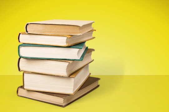 Stack of hardcover books on a yellow background with copy space for text