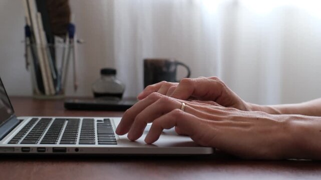 Close-up of hand using laptop trackpad at home office desk 在宅ワーク環境でノートパソコンのトラックパッドを操作する手元のクローズアップ