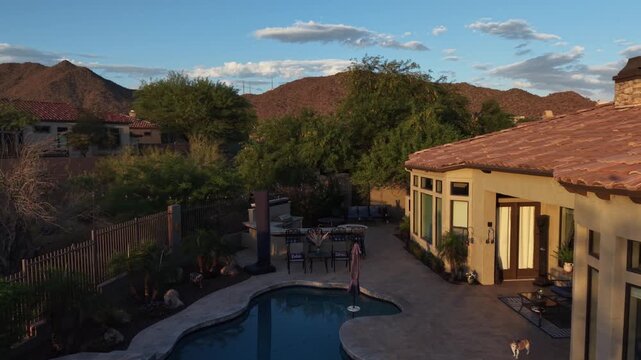 An aerial view of a desert landscaped backyard in Arizona, featuring a travertine pool deck with spa, outdoor BBQ and fireplace.