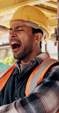 Break, tired and man with yawn at construction site, workload pressure and burnout for fatigue. Outdoor, overworked and worker with exhaustion for property development, building scaffolding or bored