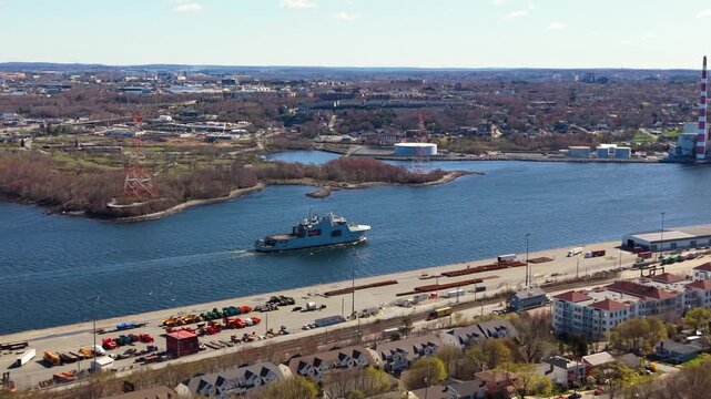 An impressive warship glides through the serene waters of Halifax Bay, highlighting Canada's commitment to maritime security and naval power in this picturesque setting