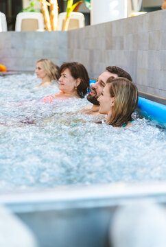 Close up of a happy young couple talking and relaxing in a crowded hot tub at a modern wellness center