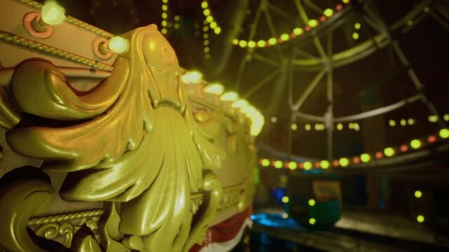 Warm textured ornament with painted scrollwork details. Shallow focus image capturing golden carousel ornament with detailed scrollwork and glowing lights