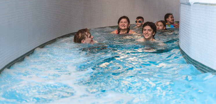 Large group of happy clients and families swimming down a lazy river stream at an indoor water park