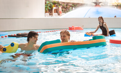 Naklejka premium Large group of friends and family playing with pool floats and enjoying time at an indoor water park