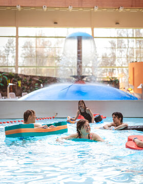 Large group of friends and family playing with pool floats and enjoying time at an indoor water park