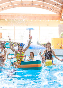 Happy hildren raising hands and playing with pool floats at an indoor water park