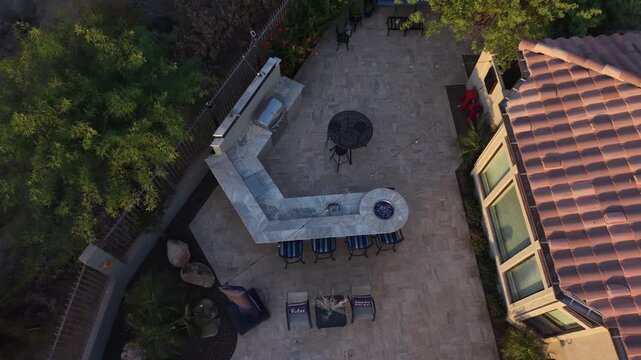 An aerial view of a desert landscaped backyard in Arizona, featuring a travertine pool deck with spa, outdoor BBQ and fireplace.