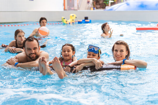 Portrait of a happy family smiling and looking at the camera while relaxing with pool floats at an indoor water park