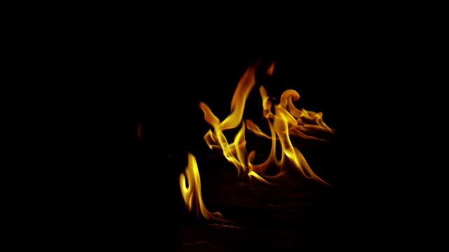 Dynamic bright yellow and orange fire flames burning on black background.